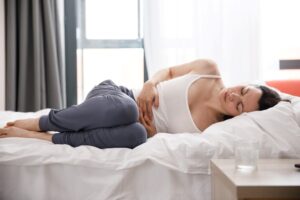 A woman holding her stomach in pain while battling digestive issues.