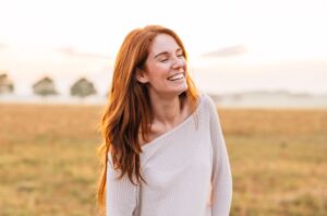 A woman smiling in a grass field.