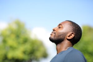 A relaxed man standing outside and basking in the sunlight.