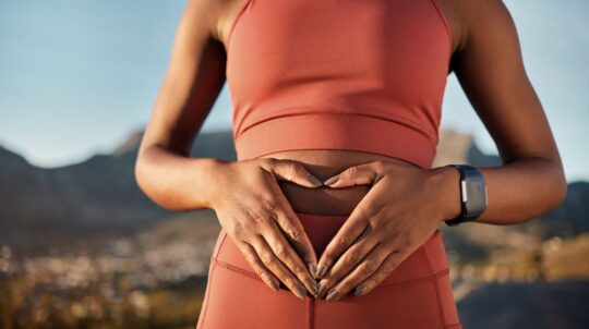 A woman holding her stomach to signify good gut health.