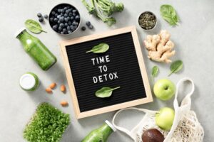 Time to detox letter board quote on a table top with fruits and vegetables.