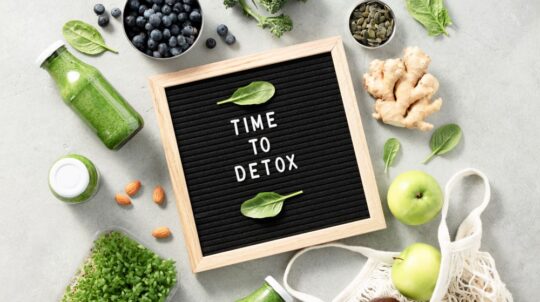Time to detox letter board quote on a table top with fruits and vegetables.