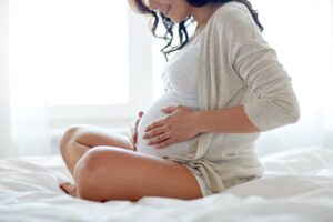 Close up of happy pregnant woman in bed at home.