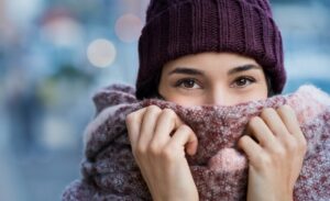 Woman holding her scarf over her face during the winter.