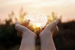 Woman holding image of brain in her hands during a sunset.