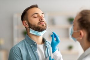 Doctor using swab stick to take covid virus specimen from potentially infected man.