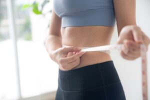 A woman measuring body proportions after boosting metabolism and losing weight.