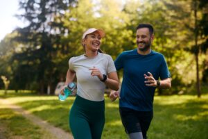 An energized couple running through the park together.