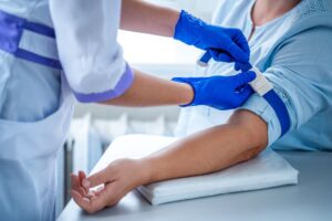 A woman receiving an EBOO treatment and getting her blood drawn by a nurse.